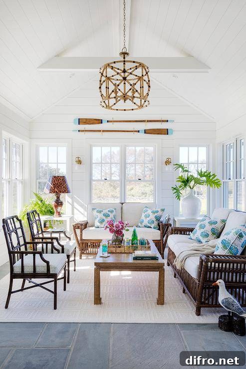A living room with brown rattan sofas and white cushions, centered on a white rug and gold chinoiserie table.