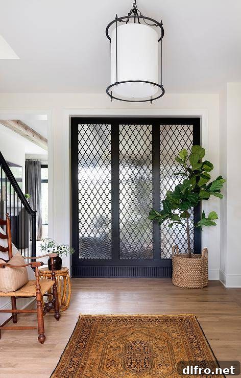 Foyer with leaded glass windows, fiddle leaf fig in a woven basket, and antique wood furniture.