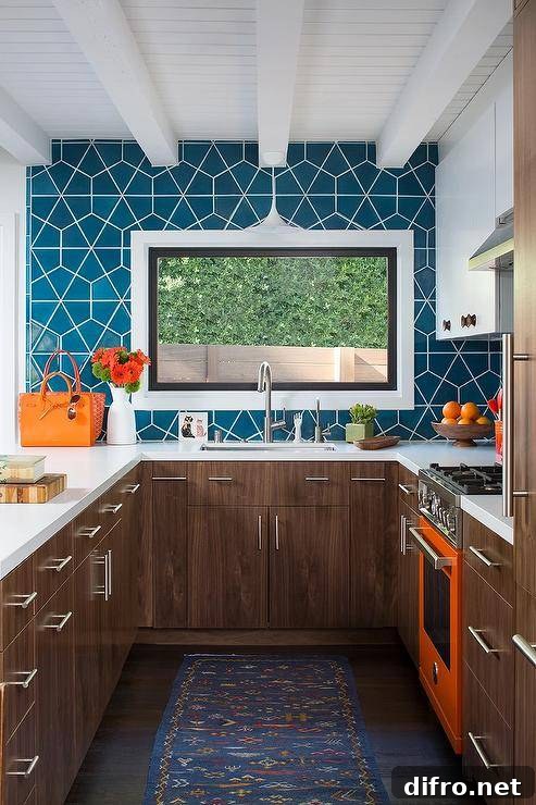 Charming brown, orange, and blue u-shaped kitchen boasts an orange stove placed between brown veneer cabinets donning satin nickel hardware.
