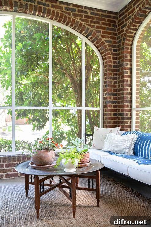 Red brick sunroom features a black daybed and a Moroccan style round hammered metal coffee table