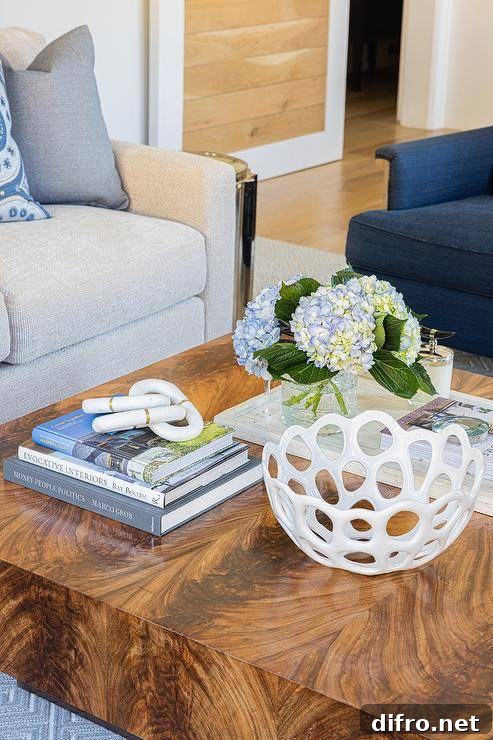A styled brown lacquered pedestal coffee table is placed in front of a light gray sectional