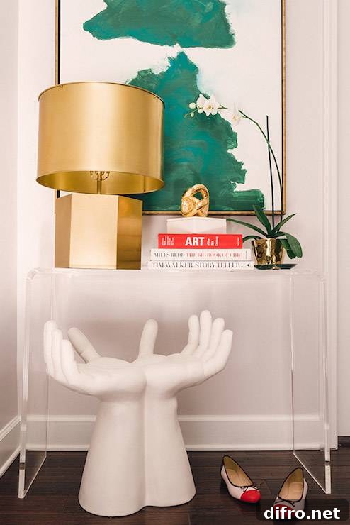 Stylish entryway with clear console table, gold accents, and emerald art.