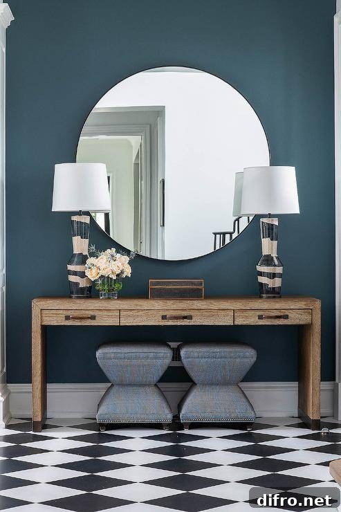 Dark foyer with wooden console table, a large round mirror, and charcoal gray stools.
