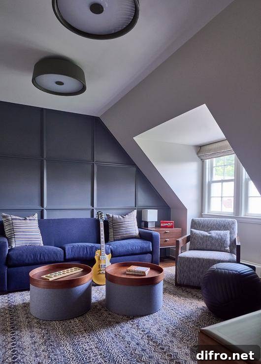 Attic family room features a blue couch on a blue paneled accent wall and round blue and brown tray coffee tables atop a blue rug and a blue accent chair.