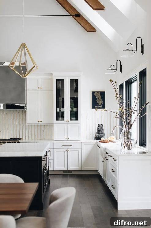 White and black kitchen features a brass geometric lantern hung over a black island topped with a marble countertop.