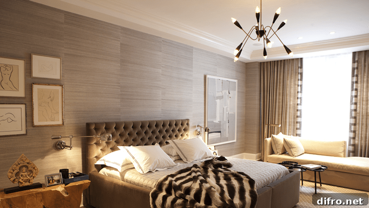 Gray bedroom with gray grasscloth wallpaper framing taupe velvet tufted headboard accented with white and taupe hotel bedding with taupe stitching and faux fur throw blanket flanked by polished nickel swing-arm sconces over eclectic nightstands.
