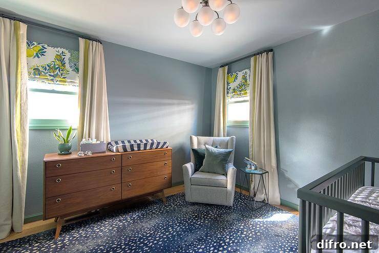 Blue boys nursery features a large blue antelope pattern area rug, a lemon print Roman shade, and a mid-century modern dresser.