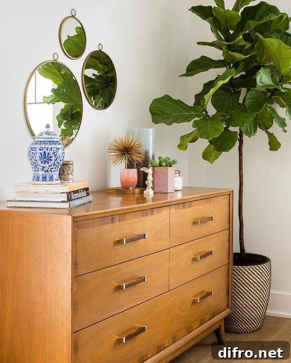 Warm toned mid-century modern dresser in a bedroom balanced by a white wall featuring three staggered round mirrors.