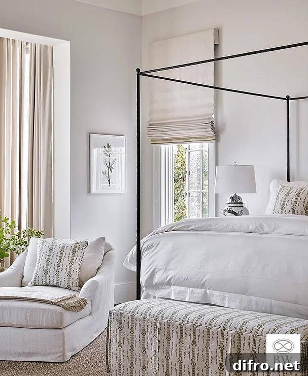 Restful bedroom complemented with a white and green upholstered bed placed at the foot of a black canopy bed contrasted with a white duvet.