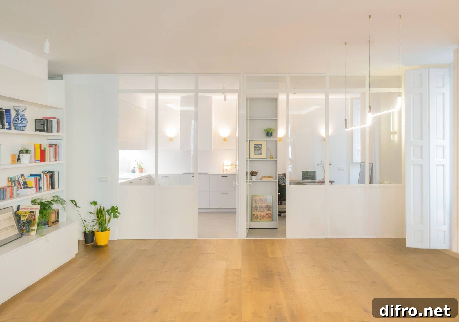 open concept living room with bookshelves lining left side, wall of windows and warm wood floors