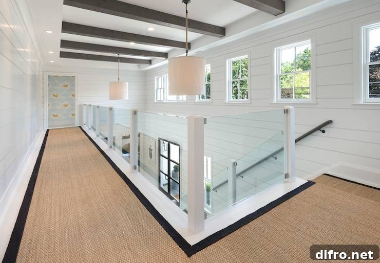 Second floor landing with clear glass stair railing and linen pendants.