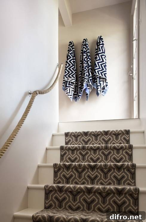 Cottage stairwell with rope railing and geometric runner.