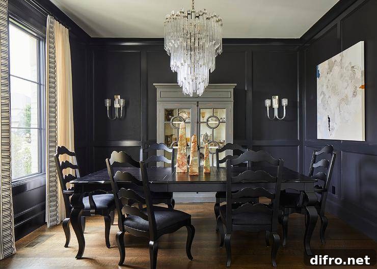 Eclectic dining room features black French ladder back chairs with a black cabriole table lit by an art deco cascading chandelier and black wall moldings.