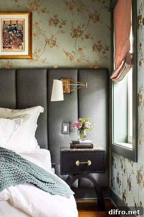 White and gold swing arm sconces on a blue art deco channel-tufted headboard in an eclectic bedroom design. A black nightstand with a black marble top pairs together with the bed and wall to wall headboard.