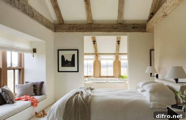 Cottage bedroom with vaulted ceiling, rustic wood beams and a window seat nook filled with pillows.