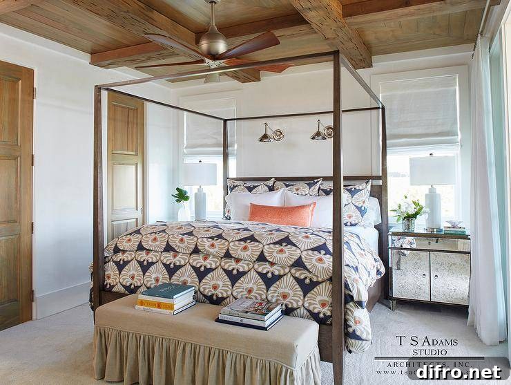 Cottage bedroom with a rustic wood coffered ceiling, canopy bed, and layered bedding in taupe and blue.