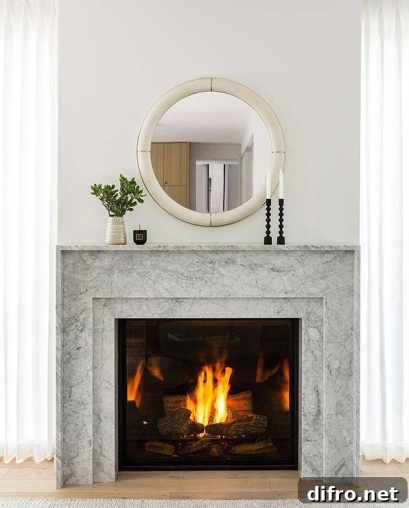 Bedroom features a round ivory shagreen mirror over a marble fireplace mantel.