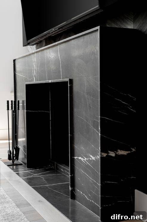 A modern honed marble black fireplace is fixed beneath a wall mount TV.