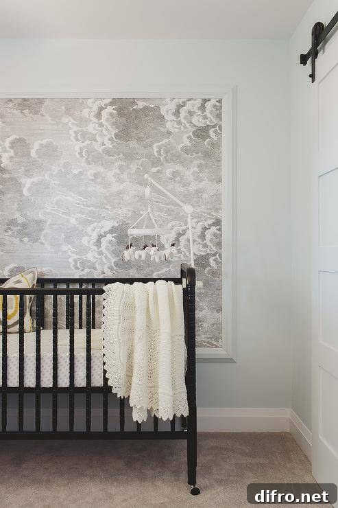 Modern boy's nursery features a horse mobile over a black nursery crib against a wall clad in cloud wallpaper.