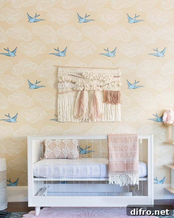 Boho nursery with light wood crib and bird motifs on the wall.