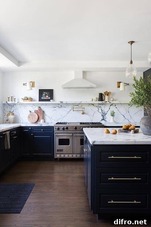 Welcoming black and white kitchen features a black island donning long thin brass pulls and a black and white marble countertop lit by vintage rippled glass pendants.