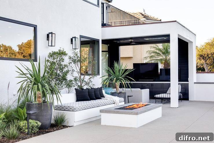 White built-in outdoor sofa upholstered with a gray and white cushion facing a gray granite fire pit.