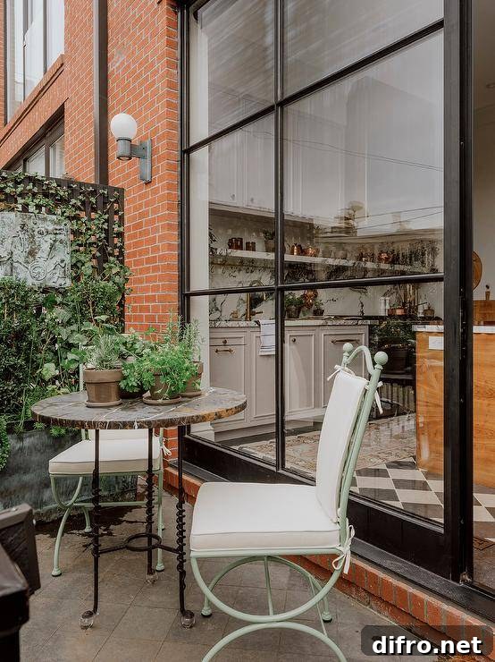 Mint green wrought iron chairs with white cushions are placed on a French style balconette at a marble bistro table.
