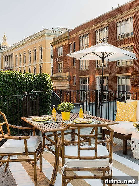 Fairy lights illuminate iron railings framing a balcony fitted with a rattan and bamboo dining table.