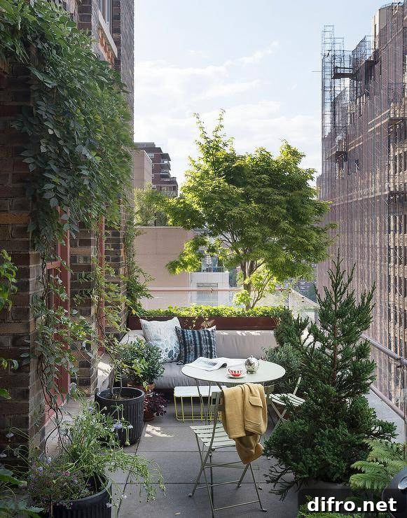 High rise balcony patio furnished with a mint green cafe table and chairs surrounded by lush green plants.