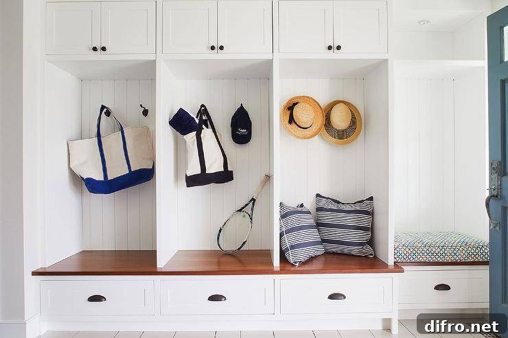 A brown wood top mudroom bench is fitted with white shaker drawers donning bronze pulls. The bench is mounted beneath open lockers boasting oil rubbed bronze hooks mounted to shiplap trim under white cabinets iwth oil rubbed bronze knobs.
