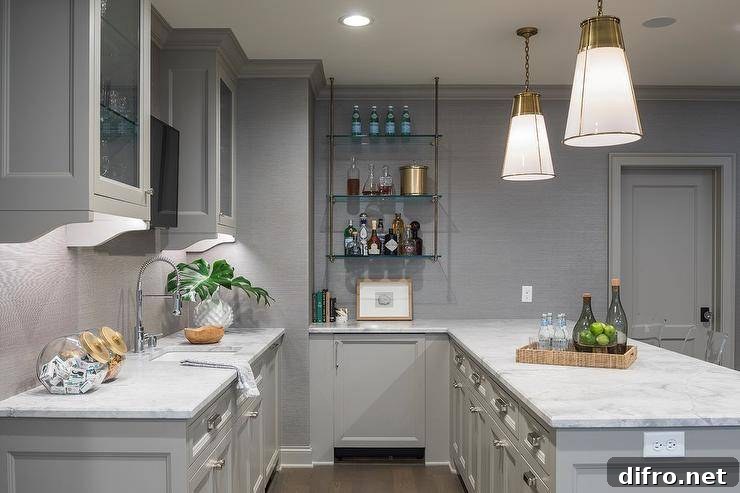 Gray wet bar lit by glass and brass pendants with Calacatta-inspired quartz countertop and glass front cabinets.