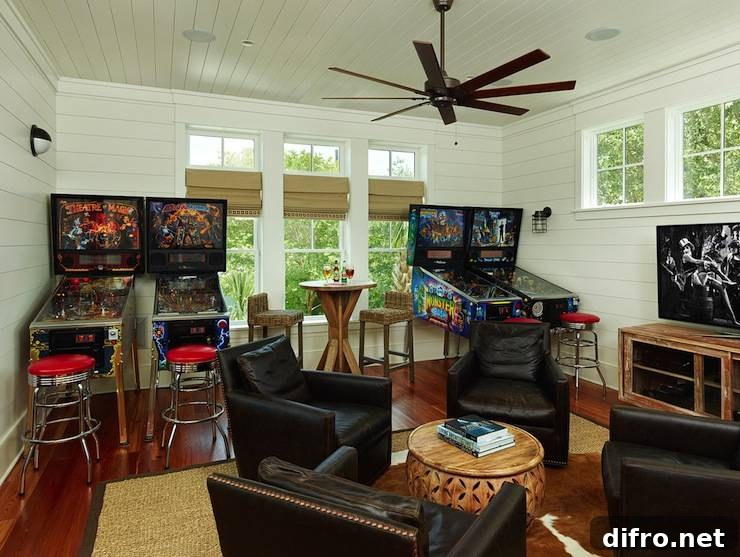 Games room with pinball machines, chrome bar stools, leather club chairs and media console