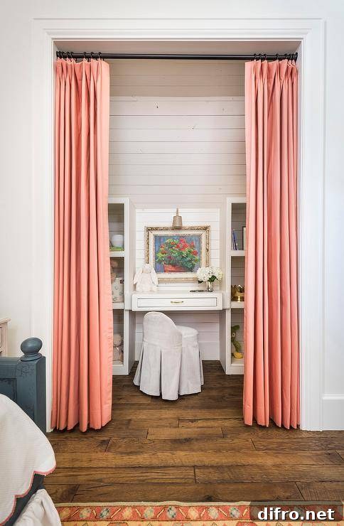 Cozy desk nook with pink curtains and a white built-in desk flanked by shelving and a skirted chair.