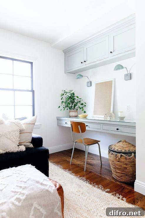 Cozy family room with a light gray floating desk, vintage wood and metal chair and green glass task lights under cabinets.