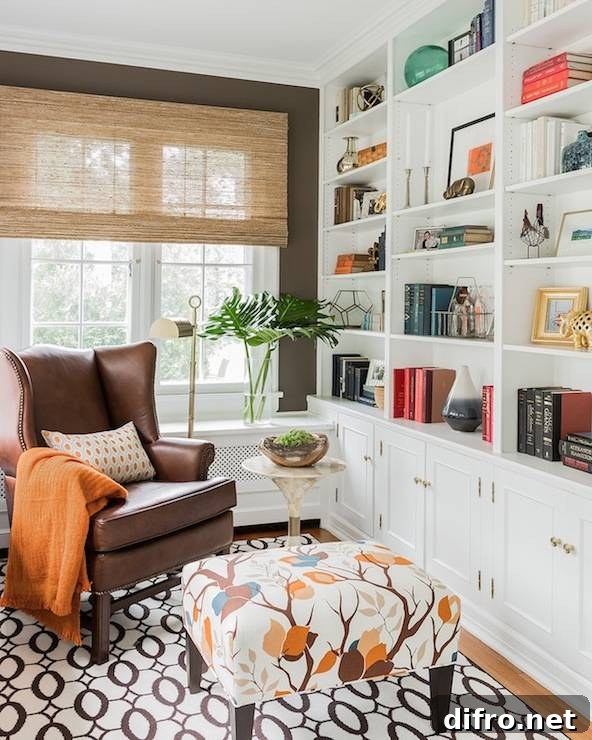 Gorgeous den features a brown leather wingback chair adorned with a pumpkin orange throw.