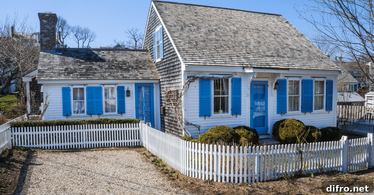 Older Cape Cod style house with white fencing.