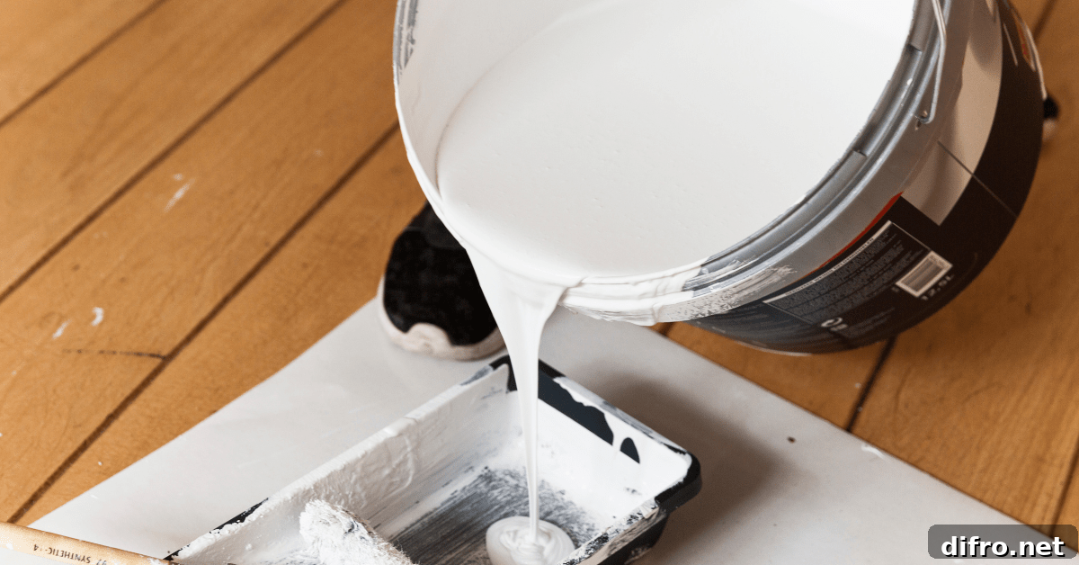 Pouring primer from a bucket into a roller pan.