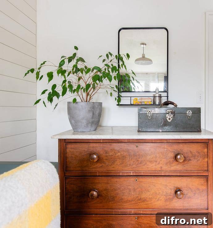 Country bedroom styled with a vintage wooden dresser topped with marble and styled with farmhouse decor.