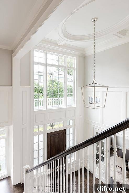 Two story foyer features wainscoting lit by a Darlana lantern.