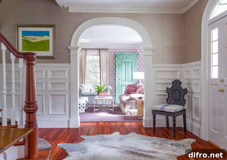 Foyer boasting stacked wainscoting and gray grasscloth wallpaper finished with a vintage gray chair and a cowhide accent rug on oak wood floors.