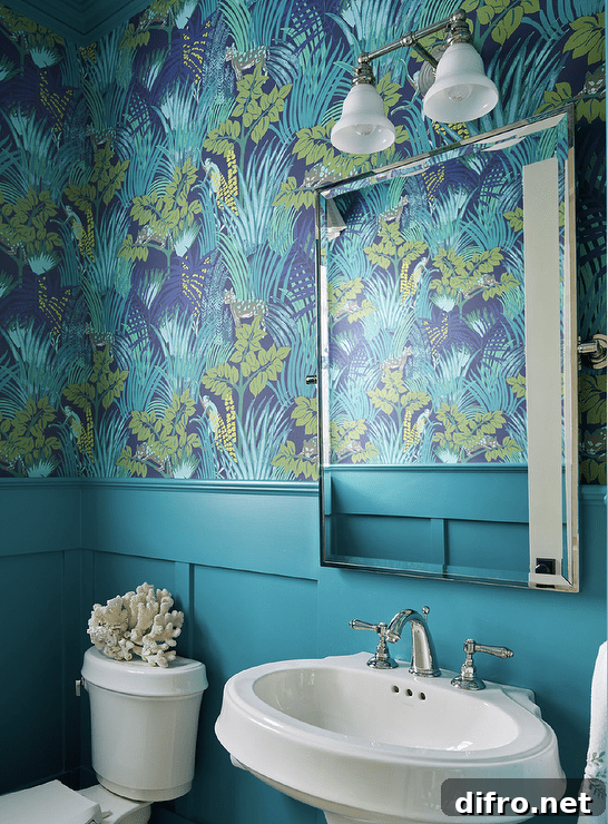 Blue powder room with blue wainscoting features an oval pedestal sink under a beveled mirror.