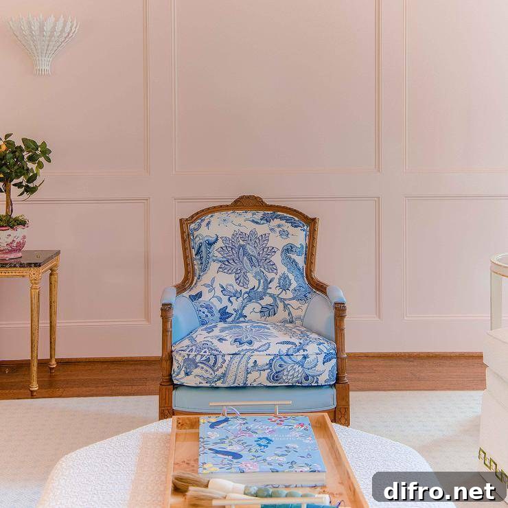 A gold French chair finished with blue chinoiserie fabric placed in front of a wainscot wall.