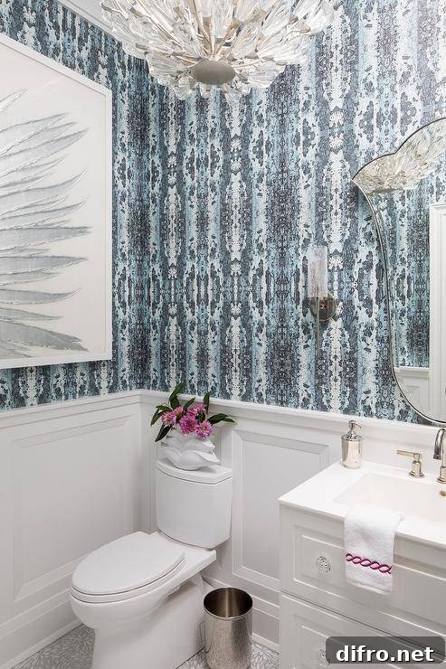 White and blue powder room features blue wallpaper over white wainscoting.