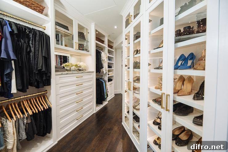 Custom walk-in closet with glass shoe cabinets and interior lighting.