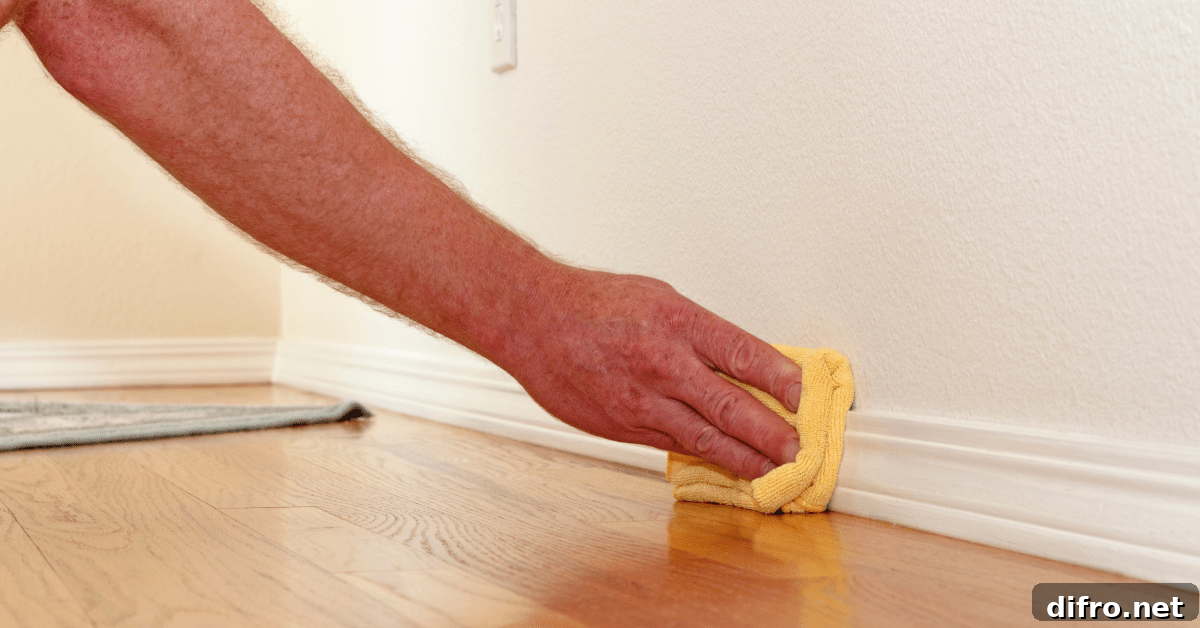 A hand using microfiber to clean baseboards.