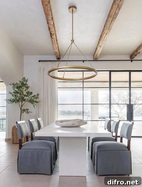 Ceiling Design Ideas to Add Personality to Your Home 6 A brass ring chandelier with wooden ceiling beams illuminates a white pedestal dining table with gray skirted slipper chairs.