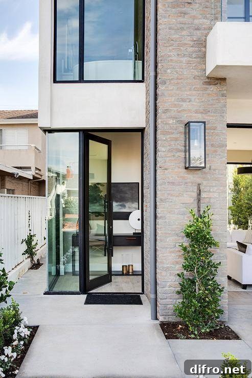 Modern brick beach home with glass windows and lush green plants.
