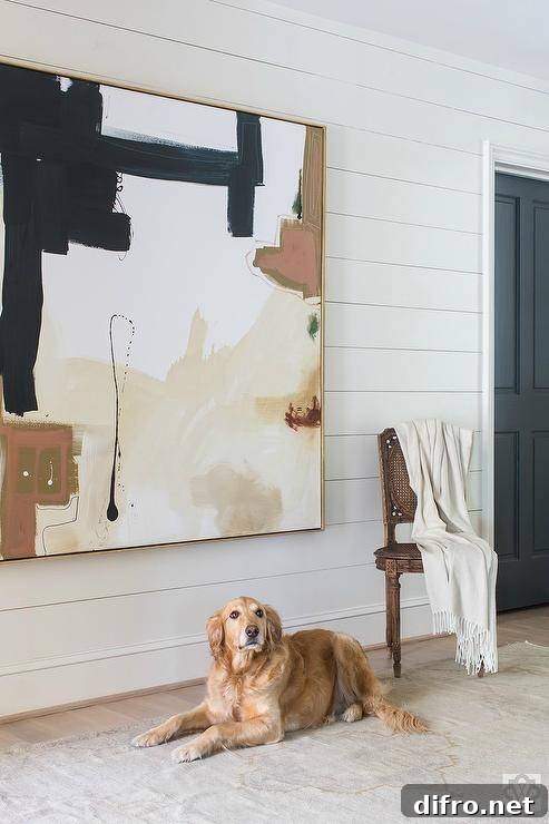 Large abstract artwork in beige and black tones displayed on a shiplap wall.