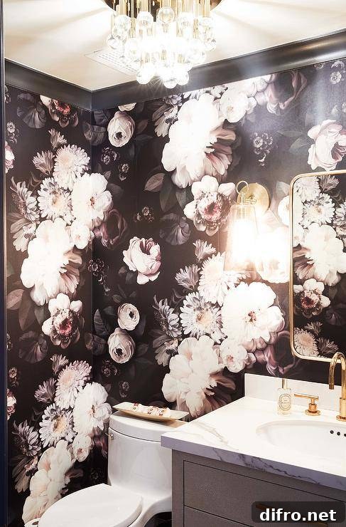 Powder room covered in dark floral wallpaper with brass mirror and gray vanity.