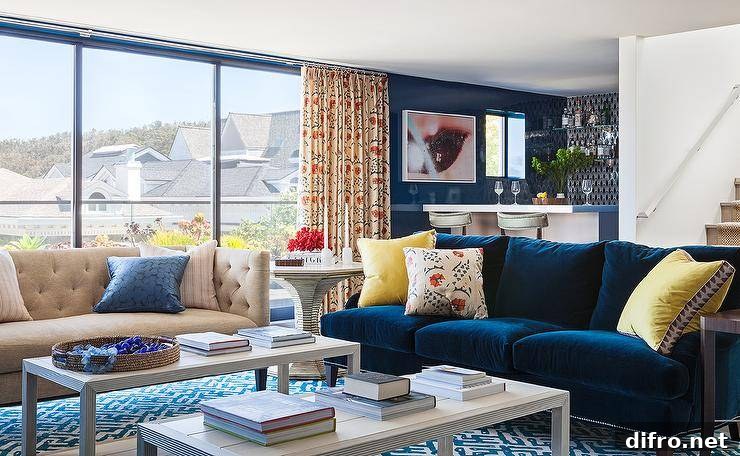Jewel blue velvet sofa with bright yellow pillows on a geometric rug.